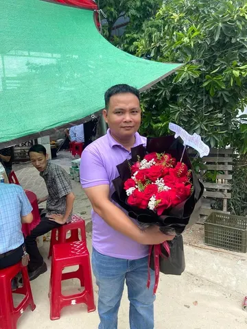 Khách nam nhận bó hoa hồng đỏ bọc giấy đen