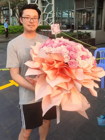 Khách nhận bó hoa hồng phấn bọc giấy cam đào giao tận nơi