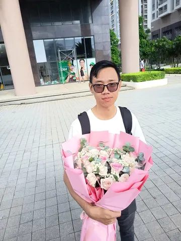 Khách nam nhận bó hoa hồng phấn lớn bọc giấy hồng