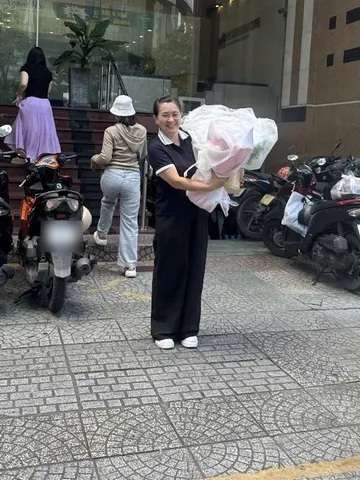 Khách nữ cười tươi nhận bó hoa hồng trước toà nhà văn phòng