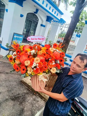 Khách nhận giỏ hoa đồng tiền tone cam chúc mừng