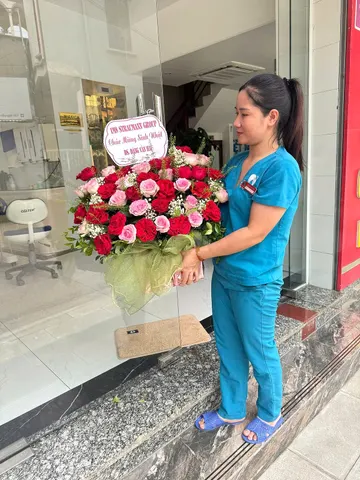 Nhân viên phòng khám nhận giỏ hoa hồng đỏ chúc mừng