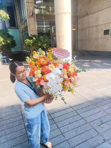 Khách nhận lẵng hoa lan hồ điệp mix hoa tone cam