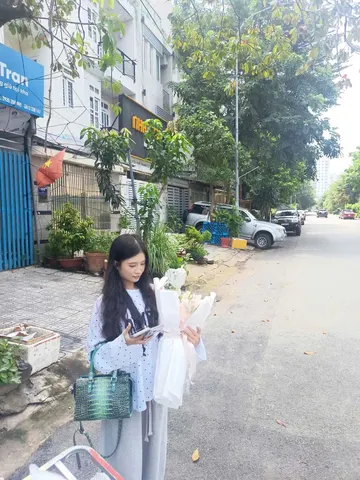Khách nữ nhận bó hoa bọc giấy trắng do Hoarosa giao tận nơi